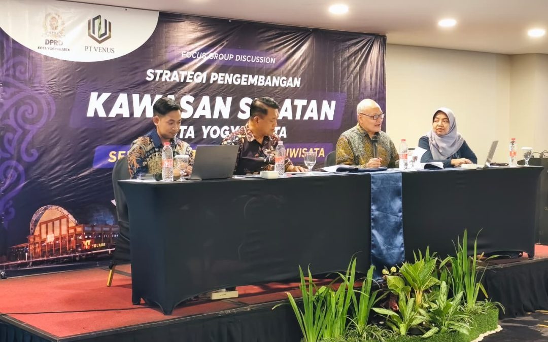 Four panelists sit at a black table on a stage with a purple banner about regional development strategies in the background, microphones and laptops visible on the table.